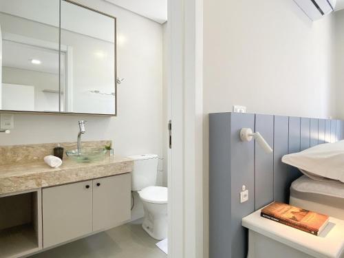 a bathroom with a sink and a toilet and a mirror at Apê Cheio de Estilo - Campeche - SDI002 in Florianópolis