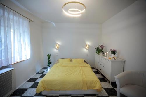 a white bedroom with a yellow bed and a window at Birdnest Apartment in Budapest