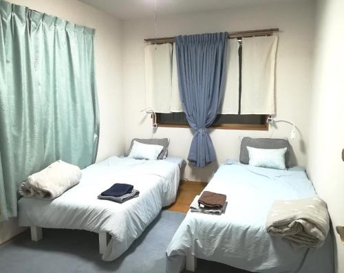 two beds in a room with blue curtains at 8-17 Nomura Motomachi - House / Vacation STAY 1893 in Hirakata