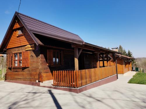 a small wooden house with a porch and a fence at Kuća za odmor Šumska idila in Velika Gorica
