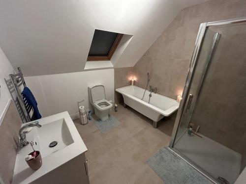 uma casa de banho com uma banheira, um WC e um lavatório. em An Teach Bán em Falcarragh