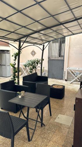 patio con tavolo e sedie sotto un baldacchino di Il cortiletto28 Rooms & House a Siracusa