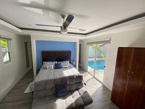 een slaapkamer met een bed, een bank en een plafondventilator bij Playa Potrero - modern 3 BR home centrally located - Casa Coastal Serenity in Guanacaste
