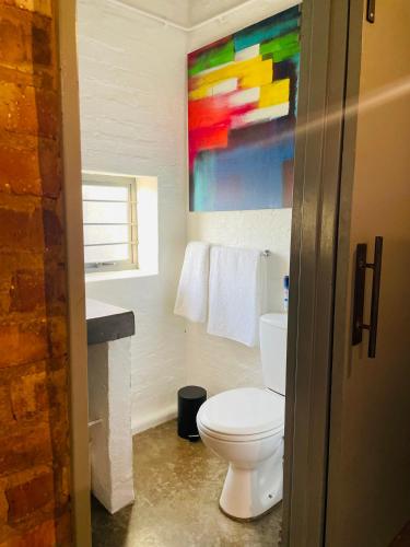 La salle de bains est pourvue de toilettes et d'une peinture murale. dans l'établissement Golden Maboneng, à Johannesbourg