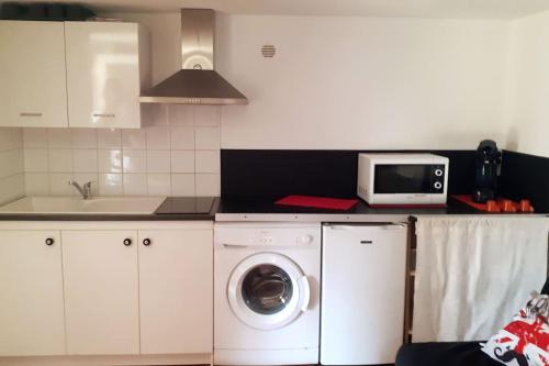 une cuisine avec un lave-linge et un micro-ondes dans l'établissement Au lit, on dort, à Cantaron