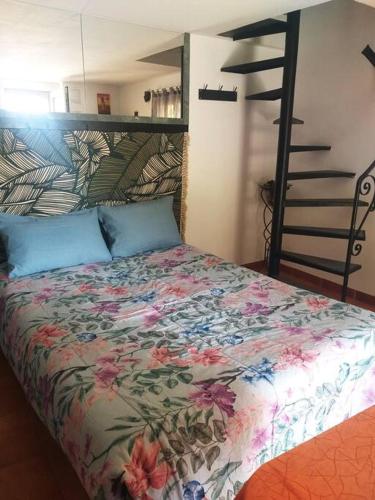 - une chambre dotée d'un lit avec un couvre-lit floral et une échelle dans l'établissement Au lit, on dort, à Cantaron