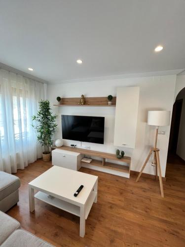 sala de estar con TV y mesa blanca en Apartamento Fana, en Cangas de Onís
