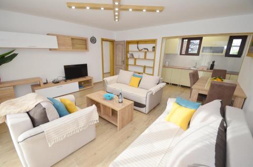 a living room with two white couches and a kitchen at DC Apartment D in Kotor