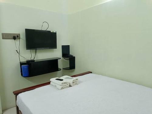a bedroom with a bed with a tv on the wall at TS-K-MARVELL in Rāmeswaram