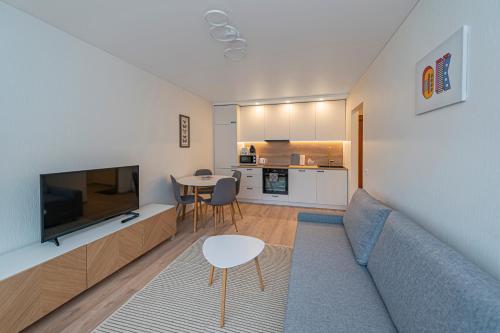 salon z kanapą, telewizorem i stołem w obiekcie Luminious apartment with balcony by Polo Apartments w Kownie