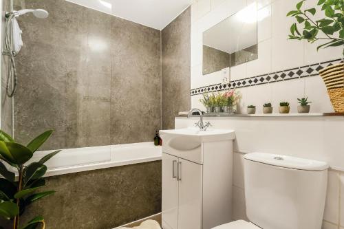 a bathroom with a toilet and a sink and a tub at Spacious 2-Bedroom Main Door Apartment With Private Parking in Glasgow