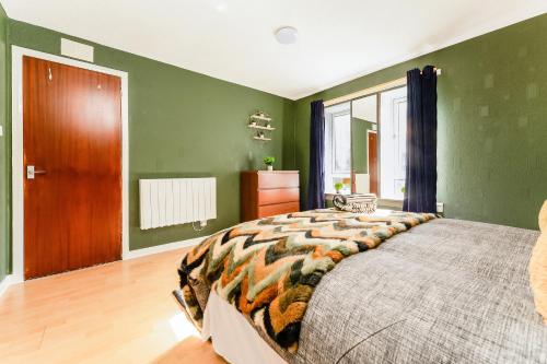 a bedroom with green walls and a large bed at Spacious 2-Bedroom Main Door Apartment With Private Parking in Glasgow