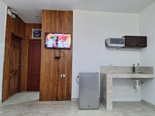 a kitchen with a refrigerator and a tv on a wall at Hospedaje Familiar Taos in Punta Blanca