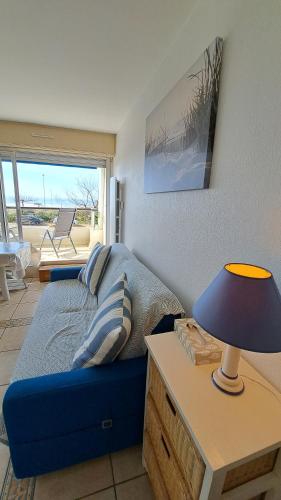 une chambre avec un canapé bleu et une table avec une lampe dans l'établissement PLEINE MER - Studio Vue mer à 30m de la plage, à Saint-Jean-de-Monts