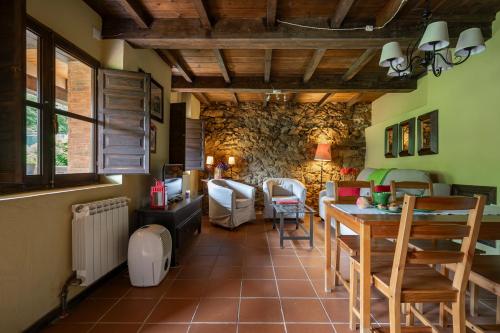 a living room with a table and chairs and a stone wall at L´Agüera de Soberron in Llanes