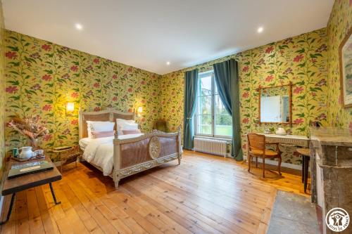 Dormitorio con papel pintado con motivos florales, cama y escritorio en Domaine du Chateau Vert en Hondainville