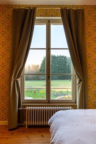 a bedroom with a window with a view of a field at Domaine du Chateau Vert in Hondainville