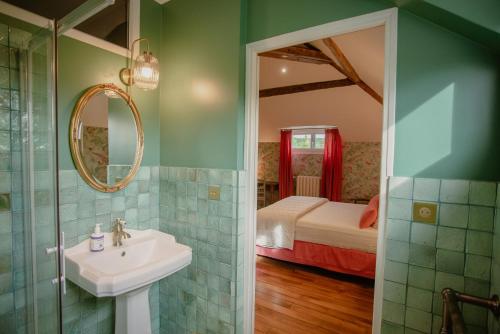 a bathroom with a sink and a bedroom with a bed at Domaine du Chateau Vert in Hondainville