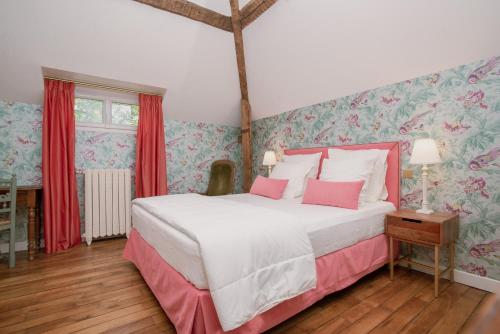 a bedroom with a large bed with pink pillows at Domaine du Chateau Vert in Hondainville