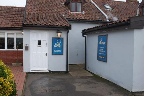 a white house with a white door and a building at The Half Moon Inn Rushall IP21 4QD in Pulham Saint Mary the Virgin