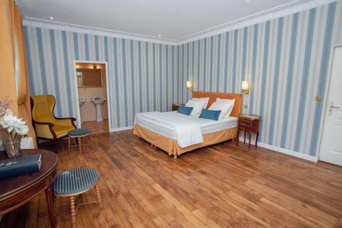 a hotel room with a bed and a table and chairs at Domaine du Chateau Vert in Hondainville
