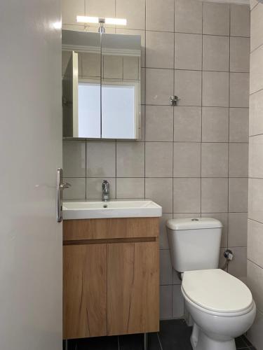 a bathroom with a toilet and a sink and a mirror at White Apartment in Kavala