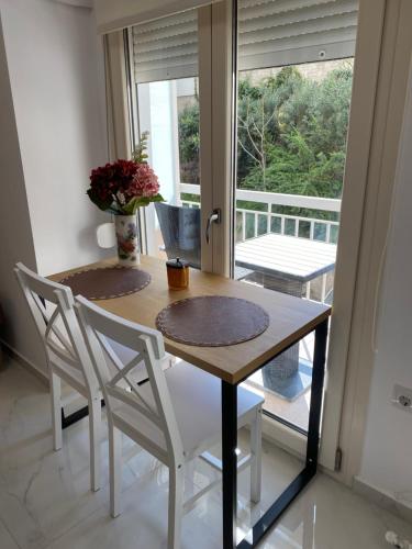 a dining room table with two chairs and a window at White Apartment in Kavala
