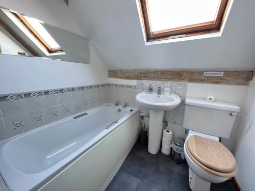 ein Badezimmer mit einer Badewanne, einem Waschbecken und einem WC in der Unterkunft Dairy Cottage in Cockley Cley