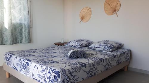 un lit avec des draps et des oreillers bleus et blancs dans l'établissement L'albizia, à Les Anses-d'Arlet