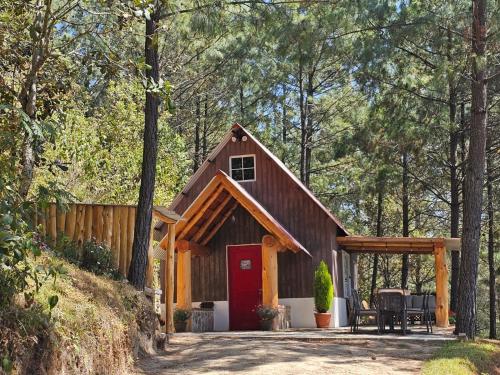a cabin in the woods with a red door at Finca Chuchiyá cabañas Tecpan in Tecpán Guatemala