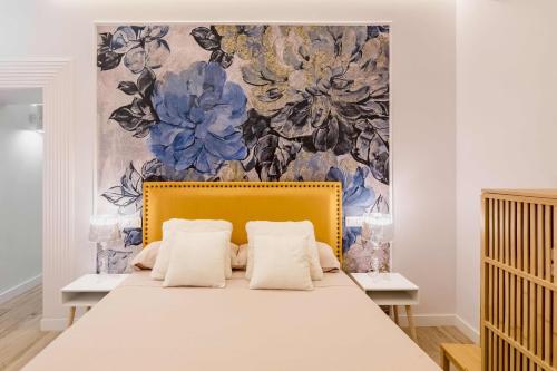 a bed with two pillows in front of a floral wall at Apartamento lujoso cercano al centro de Madrid in Madrid