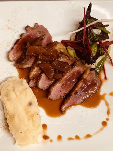 a white plate of food with meat and vegetables at Hostellerie Au rendez-vous des amis in Chaumont