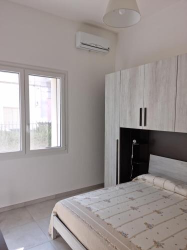 een witte slaapkamer met een bed en twee ramen bij VILLA BIANCA Porto Cesareo in Porto Cesareo