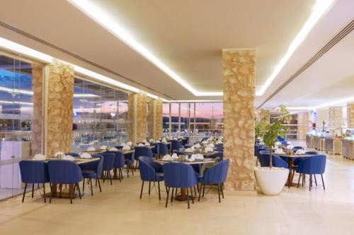 a restaurant with blue tables and chairs and windows at Pickalbatros Vita Resort - Portofino Marsa Alam in Abu Dabab