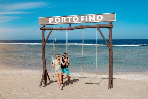 two people riding on a swing on the beach at Pickalbatros Vita Resort - Portofino Marsa Alam in Abu Dabab