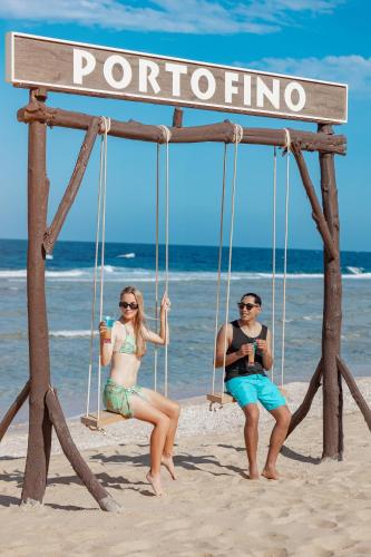 a man and woman sitting on swings on the beach at Pickalbatros Vita Resort - Portofino Marsa Alam in Abu Dabab