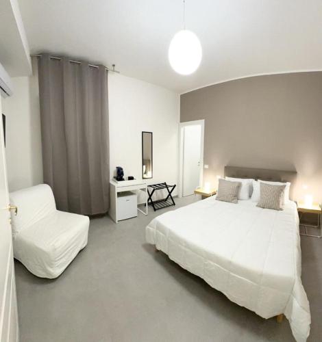 a bedroom with a large white bed and a chair at 4Th Floor Caserta in Caserta
