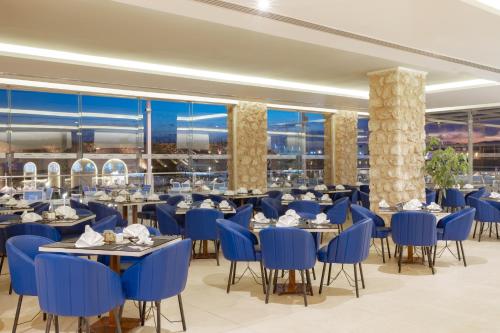 a restaurant with blue chairs and tables and windows at Pickalbatros Vita Resort - Portofino Marsa Alam in Abu Dabab