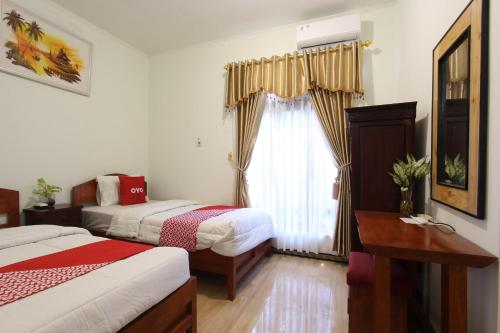 um quarto de hotel com duas camas e uma janela em OYO 93789 Mbah Carik Homestay em Magelang