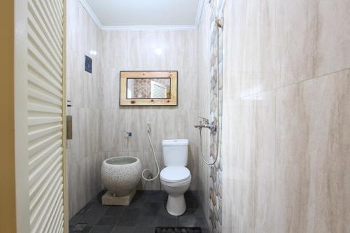 uma casa de banho com WC e uma fotografia na parede em OYO 93789 Mbah Carik Homestay em Magelang
