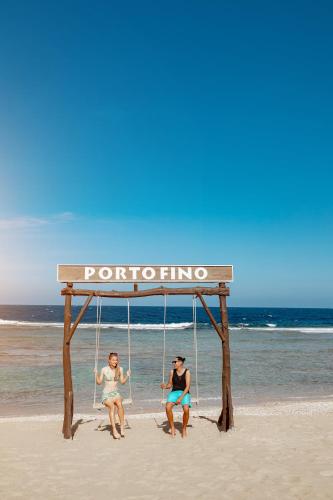 three people sitting on a swing on the beach at Pickalbatros Vita Resort - Portofino Marsa Alam in Abu Dabab