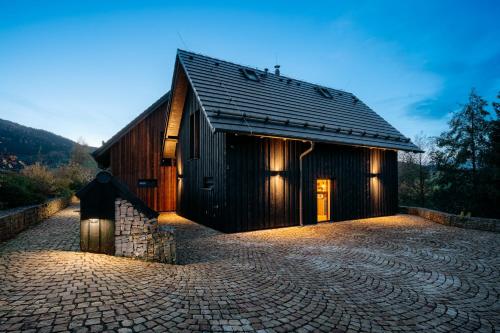 a barn with a cobblestone driveway in front of it at Chalupa Malá Venkovanka se saunou a bazénem in Božanov