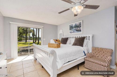 a bedroom with a bed and a chair and a window at Tomoka River Guest House in Ormond Beach