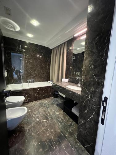 bagno con 2 servizi igienici, lavandino e specchio di The Unique Hotel a Milano
