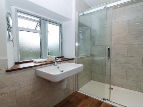 uma casa de banho com um lavatório e uma cabina de duche em vidro. em The Loft at Lucott House em Bath