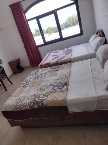 two beds sitting in a room with a window at Hotel Canarias Paso Canoas in Canoas