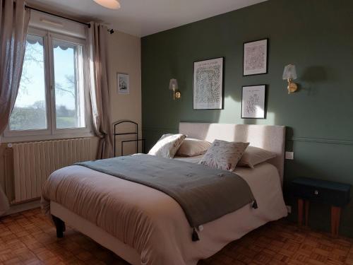 een slaapkamer met een bed met groene muren en een raam bij La Maison de Marie in Kérien