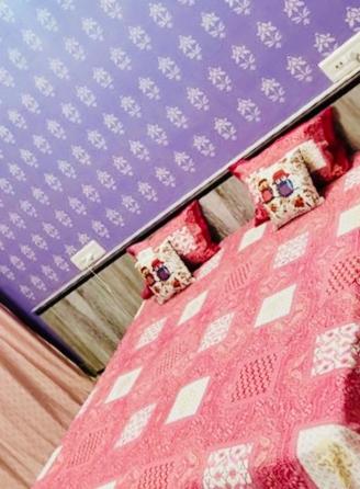 een bed met een roze deken en kussens erop bij The Desert Palace in Bikaner