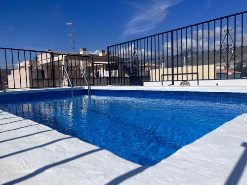 uma piscina com água azul em frente a uma cerca em Naim Guest House Nerja em Nerja