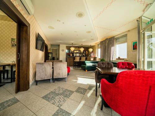 a living room with red chairs and a table at Hotel Maj Inn in Moravske Toplice